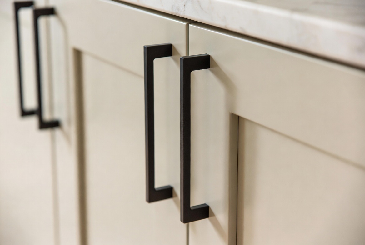 Matte black bar handles on a custom cream kitchen cabinet